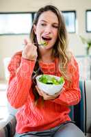 smiling woman eating a bowl of salad