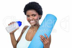 Pregnant woman holding water bottle and mat