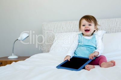 adorable Baby holding a tablet smiling at the camera