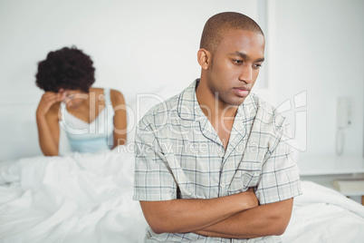 Upset man sitting on bed after argument