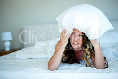 angry woman covering her head with a pillow