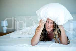 angry woman covering her head with a pillow