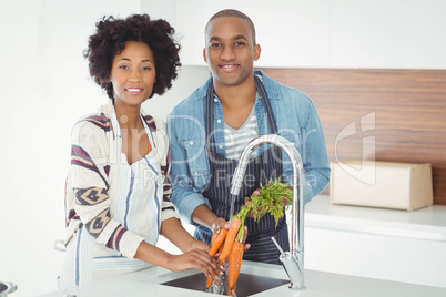 Happy couple washing carrots