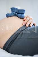 Pregnant woman with baby shoes on belly