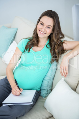 Pregnant woman writing on document