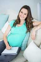 Pregnant woman writing on document