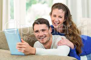 Young couple sitting on sofa and using digital tablet