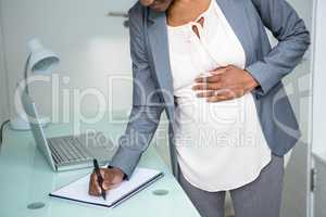 Pregnant businesswoman writing on notebook