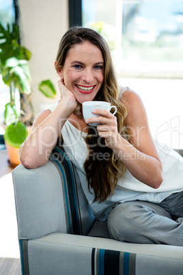 smiling woman sipping coffee in her sitting room