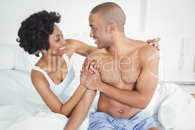 Happy couple sitting on bed