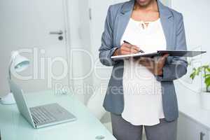 Pregnant businesswoman writing on notebook