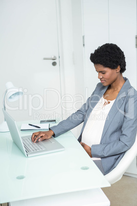 Pregnant businesswoman using laptop