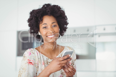 Smiling woman with earphones using smartphone