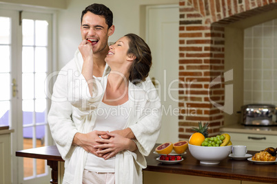 Man embracing while woman feeding strawberry to him