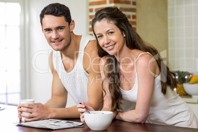 Young couple reading newspaper while having breakfast