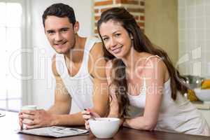 Young couple reading newspaper while having breakfast