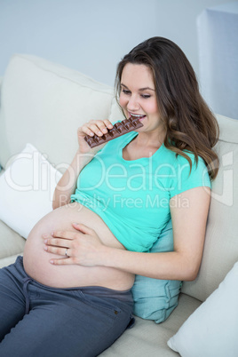 Smiling pregnant woman eating chocolate