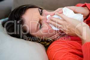 sick woman blowing her nose into a tissue
