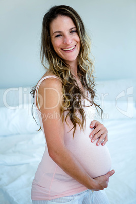 smiling pregnant woman holding her bump