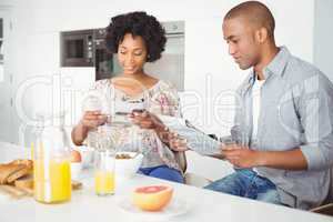 Smiling couple reading magazine and documents during breakfast