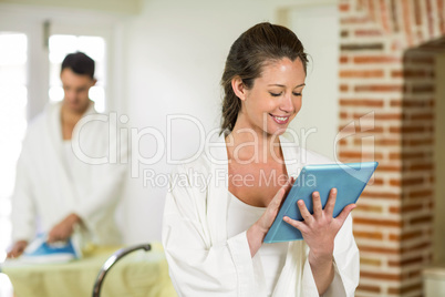 Beautiful woman in bathrobe using digital tablet