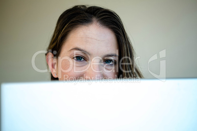 woman looking over the top of her laptop screen