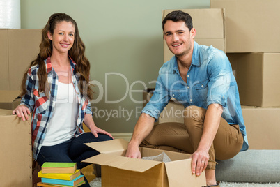 Young couple unpacking carton boxes in their new house