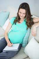 Pregnant woman writing on document