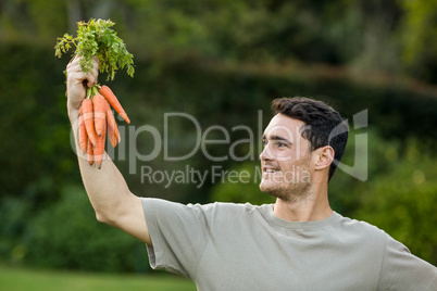 Young man holding bunch of carrots
