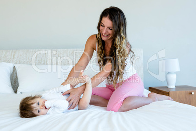 smiling woman holding a baby on a bed