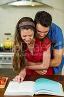 Couple embracing while checking the recipe book