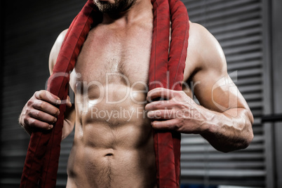 Mid section of shirtless man with battle rope around neck