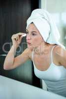 woman cleaning her skin in front of the mirror