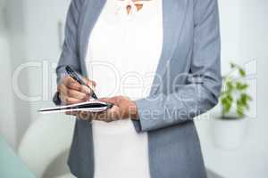 Pregnant businesswoman writing on notebook