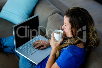 business woman sipping coffee and typing on her laptop