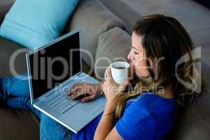 business woman sipping coffee and typing on her laptop