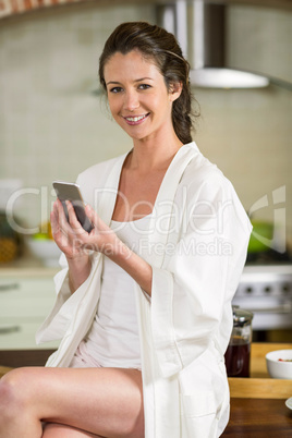 Beautiful woman in bathrobe typing a text message on smartphone