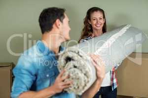 Happy couple carrying rolled up rug