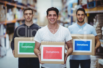 Volunteers smiling at camera holding donations boxes