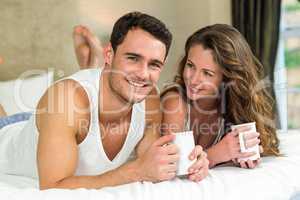 Young couple having cup of coffee on bed