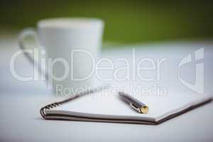 Overhead of notebook with pen and coffee