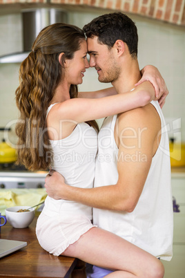 Young couple cuddling on kitchen worktop