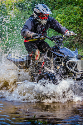 Quad rider through water stream