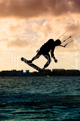 Silhouette of a kitesurfer flying