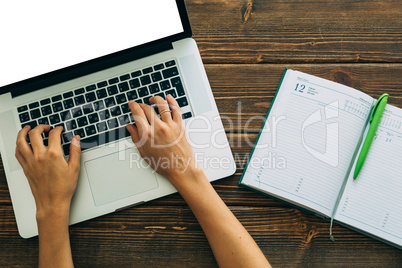 Woman working with laptop placed on wooden desk