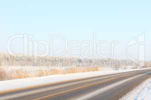 Winter road through snowy fields and forests