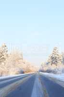 Winter road through snowy fields and forests