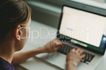 Woman working with laptop placed on wooden desk