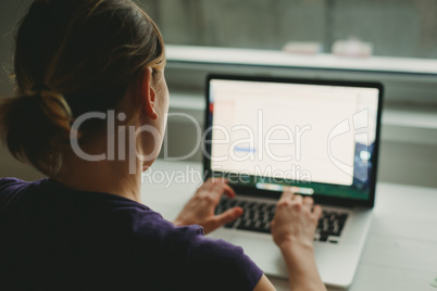 Woman working with laptop placed on wooden desk