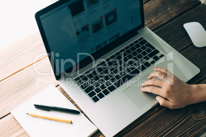 Woman working with laptop placed on wooden desk